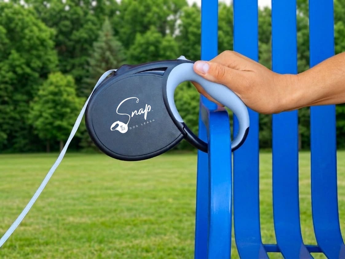 Retractable dog leash with built-in clip snapped securely onto a park bench arm
