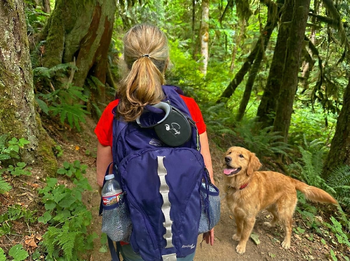 Woman hiking with her dog, the retractable dog leash clipped to her backpack to stay hands-free